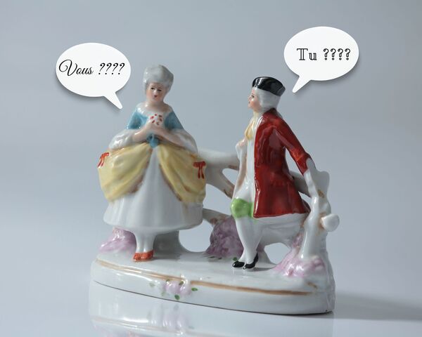 deux petits personnages en porcelaine, un homme et une femme, en vêtements du XVIIIeme siècle avec des bulles de BD disant tu ???? et vous ????