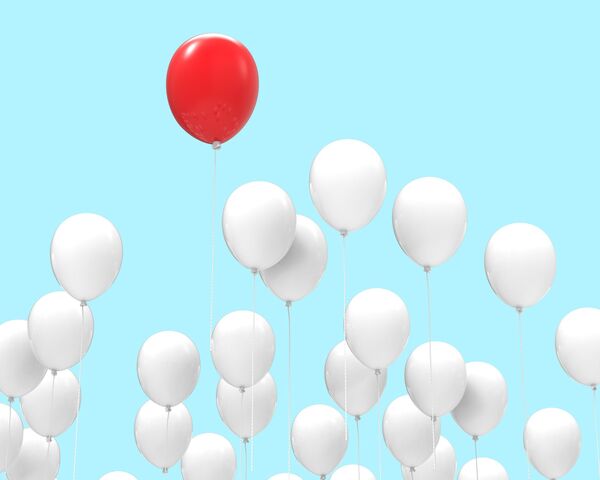 un ballon rouge au milieu de ballons blancs
